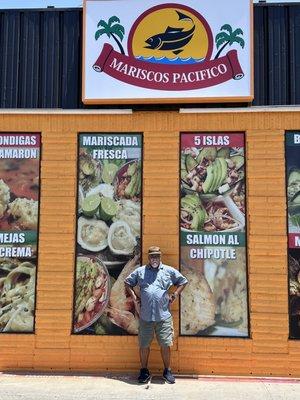 Standing outside near the entrance of the restaurant.