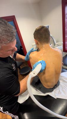 Dr. Diego Ruiz performing Softwave on Stevens Tech Wrestler's back