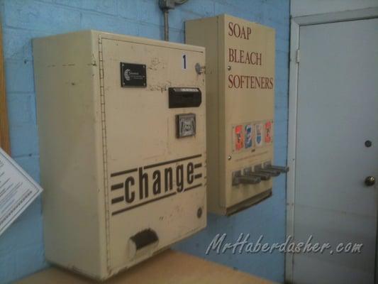 Vintage change machine next to dispenser.