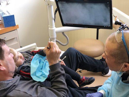 Daddy shows Jack Jack his teeth in the mirror. Training him to keep his teeth and gums healthy at 20 months.