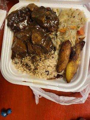 Oxtail served with rice and peas and stir-fry cabbage with two plantains