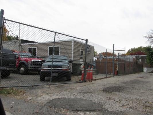 view to the entrance to the "office" trailer to Alex's towing, from street corner where Yes grocery store is on Georgia Ave NW