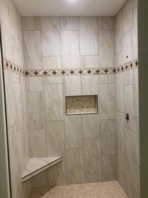 A beautiful tile shower with metal trim.