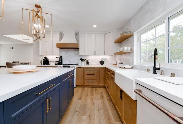 Kitchen with warm wood cabinetry, navy island, marble countertops, brass fixtures, and high-end appliances for timeless sophistication.