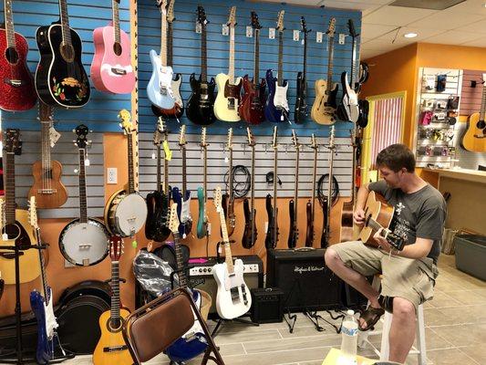 Wall of guitars, and Josh, our guitar teacher.