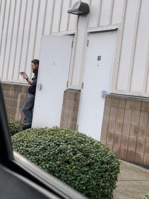 Employee, smoking in doorway of back entrance.