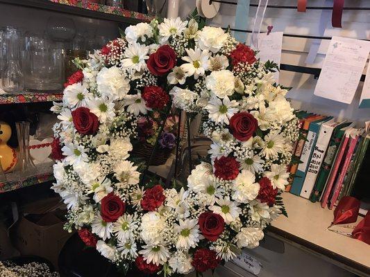 Red roses, white carnations, white daisies, baby breath and greens wreath