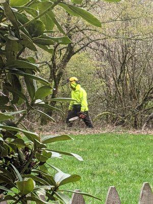 An unknown man walking through a residential yard holding a chainsaw.