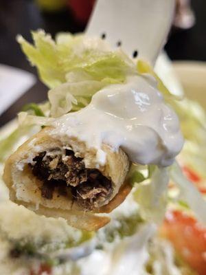 A fork holding a piece of the Tacos Dorados with the Shredded Beef inside.