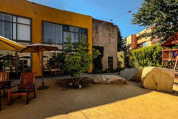 The courtyard is covered by sun shades and includes tables and chairs and a children's play area.