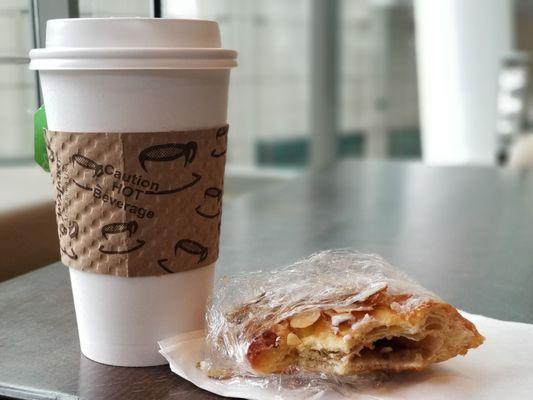 Green tea and partially eaten almond bear claw..