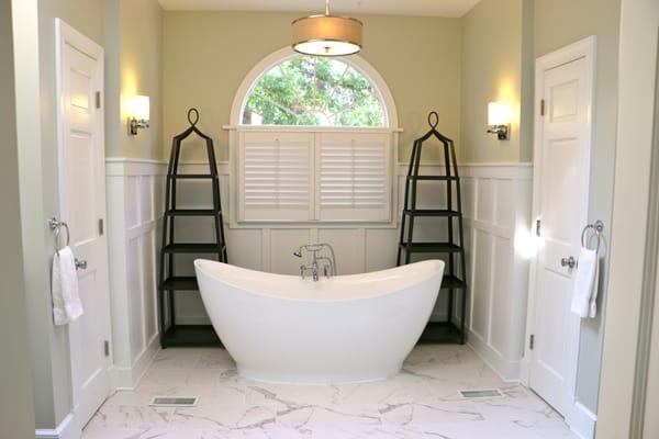 Classic porcelain marble tile setting with a relaxing freestanding tub placed in the center of a serene master bathroom.