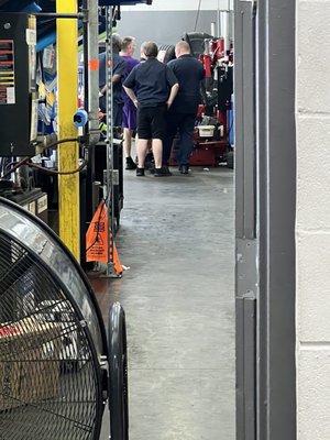 Auto service walks away from line of customers. They just hang out in the back joking around and not doing much.