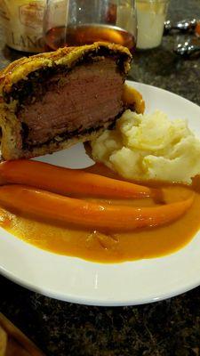 Beef Wellington in half with a portion of the sides