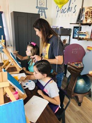 Miss Pachi guiding the kids through a painting class