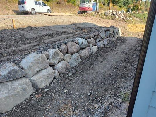 Adding a new natural rock retaining wall alongside of garage