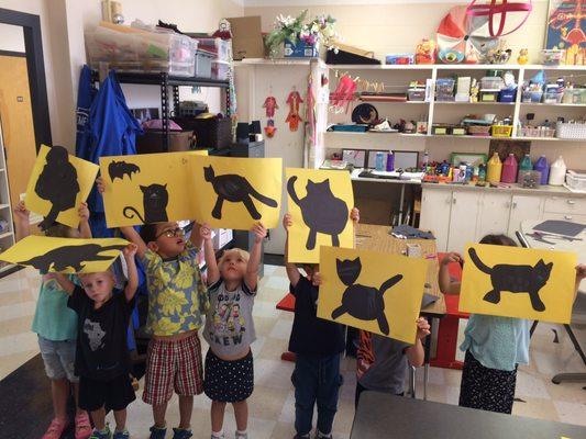 Students show off the construction paper black cats they created for Art