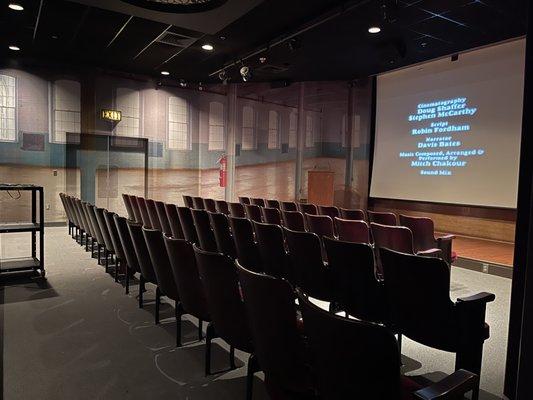 Theater equipped with vintage salvaged chairs, exit signs and ceiling decor.