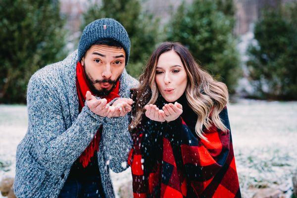 man and woman blowing snow out of their hands