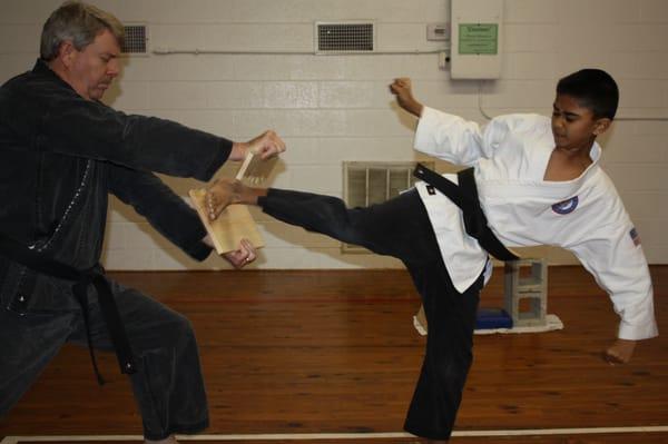 1st Degree Black Belt side kicks his way through a board.