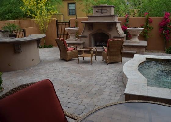 Custom fireplace with firepots, barbecue with serving counter, water feature and travertine pavers.