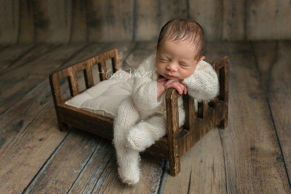 Newborn posed on a bed.