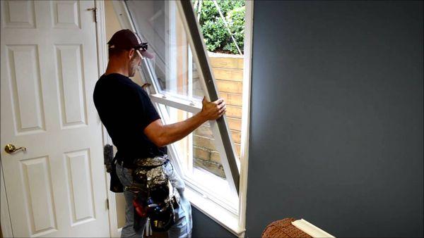 Skilled hands at work: Installing a new vinyl double-hung window with precision and expertise.