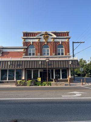 A cool building with lion sculptures across from it.