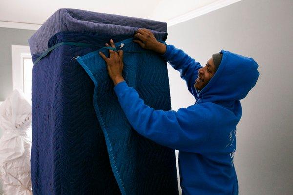 Crew member pad-wrapping furniture for a residential move.