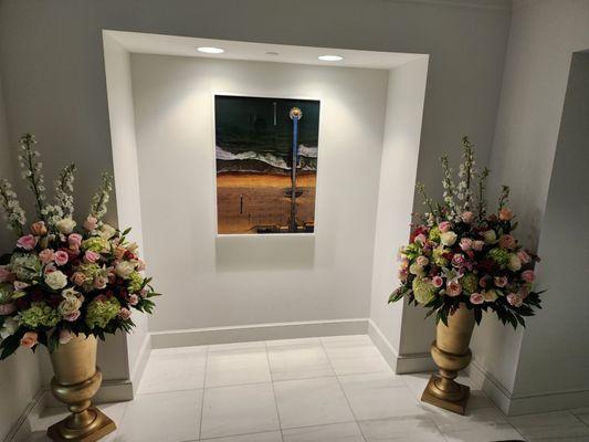 Pair of gold urns with fresh flowers at the entrance