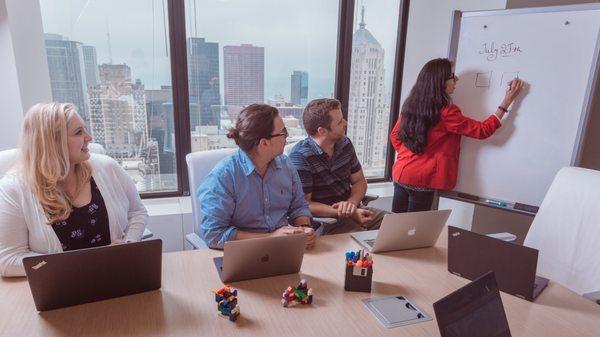 Team discussing solutions in a conference room with the skyline in the background.