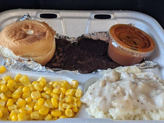 Hamburger with mashed potatoes,corn and roll. BBQ sauce on side