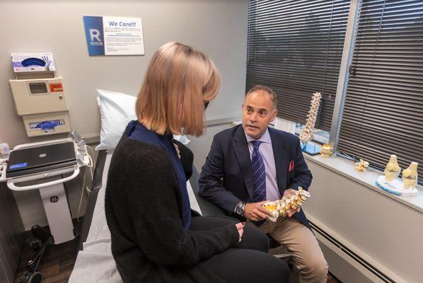 Dr. David Wells-Roth in exam room with patient holding spine model