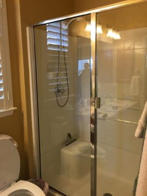 Vinyl shower surround was outdated, framed shower door and fixtures were outdated as well