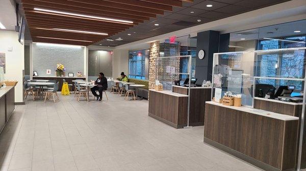 View of Cafe from cash register. Dining area in back with 9 or 10 tables.