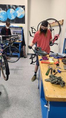 A student works on his bike after being shown a demo by a teacher.