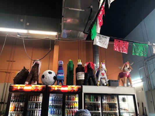 Colorful piñatas above the beverage cooler