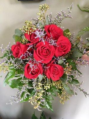 A bridesmaid bouquet with red roses, seeded eucalyptus, and limonium