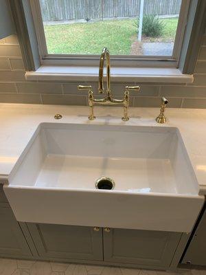 White Farmhouse sink with a brushed gold faucet