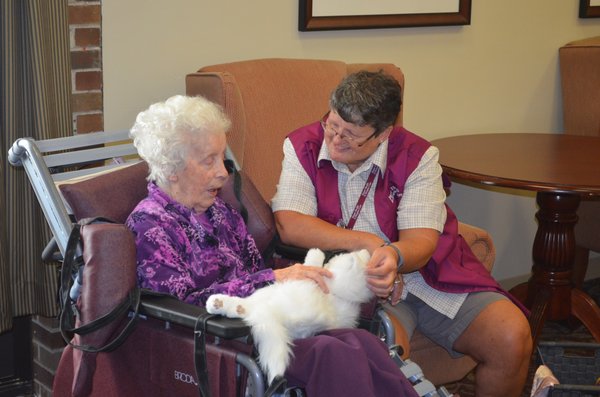 Volunteer Beth Carson shows Tinkerbell, a robotic cat, to a nursing home patient.