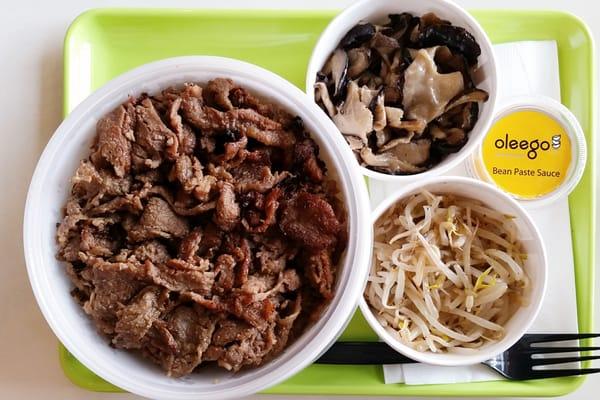 Bulgolgi over egg fried rice with bean paste sauce and banchan: bean sprouts and mushrooms.