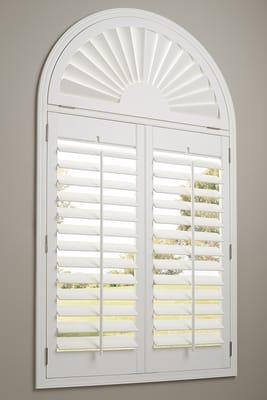 Heritance Hunter Douglas shutters  in a master bedroom, arch window with plantation shutters.