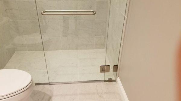 Smooth transition between bathroom floor and moveable glass partitions and fixed wall glass.