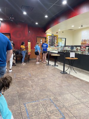 Long line and one person pushing ice cream out and cashing people out.