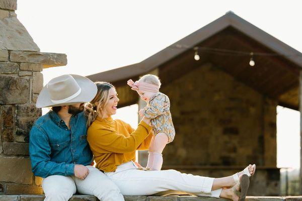 Candid family photo of mom and dad smiling at infant daughter