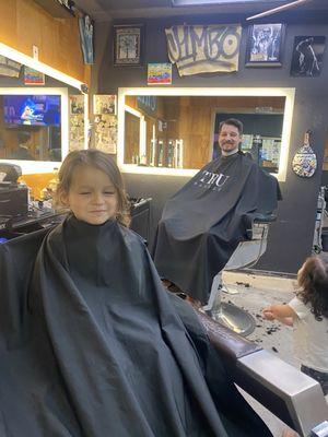 Father and son getting hair cuts at the barbers for the first time