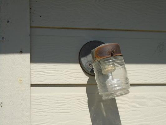 Rear exterior light fixture is rusted and not properly secured. Fixture should be replaced as it presents a shock hazard.