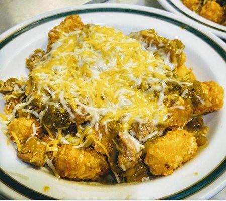 "El Borracho": Slow roasted pork green chile stew poured over crisp tots and smothered with 3 cheeses. 100% Hatch