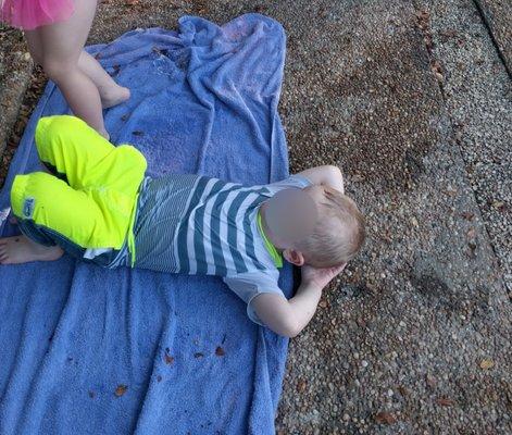 One of the Littles kicked back during the pool's "safety check". He is sort of laying on a towel, but note the pebble rock around the pool.