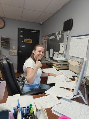 Office staff member at Advantage Air Conditioning Solutions giving a thumbs up while managing paperwork, ensuring smooth operations